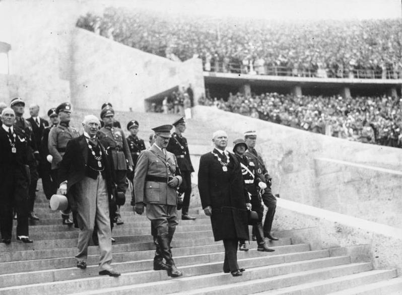 Fotografía de la entrada de Adolf Hitler, canciller y fürer del Reich (Imperio) alemán, al Estadio Olímpico de Berlín, antes del comienzo de la ceremonia inaugural de los Juegos Olímpicos de verano de 1936. a su izquierda Graf Baillet-Latour, presidente del Comité Olímpico Internacional, y a su derecha, Theodor Lewald, presidente del comité organizador de los Juegos Olímpicos de 1936 y miembro del Comité Olímpico Internacional