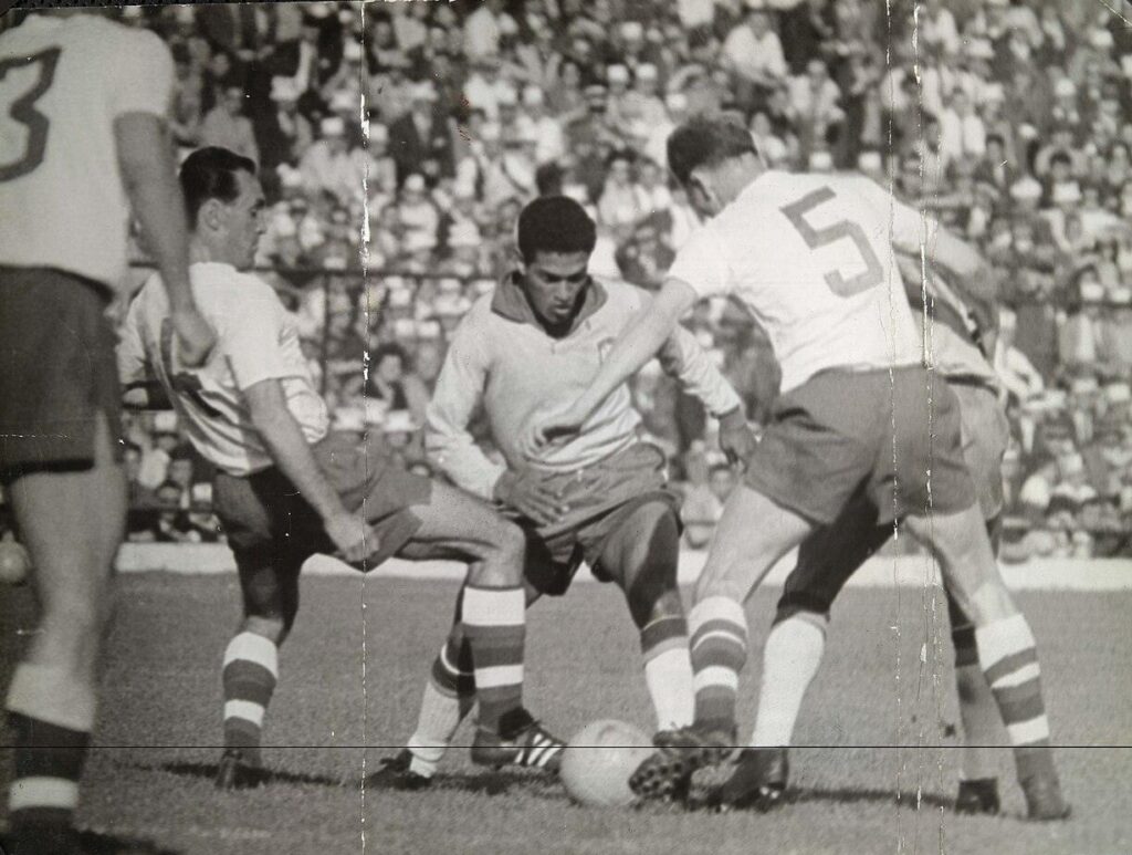 Manoel Francisco dos Santos, conocido como "Garrincha" (de frente) burla al número 4, Ladislav Novák (izquierda y de espaldas), al número 5, Svatopluk Pluskal (derecha y de espaldas), del equipo nacional de Checoslovaquia, mientras un compañero no identificable del equipo de Brasil bloquea al defensor de la derecha, en la final de la Copa del Mundo de Chile 1962, celebrada en el Estadio Nacional de Santiago, el 17 de junio de 1962. En primer plano, y casi fuera de la imagen, se ve de espaldas al número 3 de Checoslovaquia, Ján Popluhár.