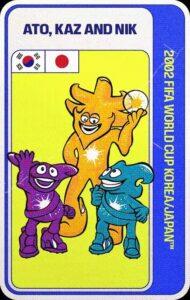 Ato, Kaz y Nik, mascotas oficiales del Mundial Corea del Sur-Japón 2002, que representan a tres figuras antropomórficas sonrientes, aparentemente alienígenas, de colores morado, amarillo y azul turquesa. El más alto de los tres, el de color amarillo, que se encuentra en el centro, tiene una esfera transparente en cuyo interior brilla una estrella de muchas puntas, mismo símbolo que los tres personajes llevan en blanco sobre el pecho.