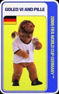 Goleo VI y Pille, mascotas oficiales del Mundial Alemania 2006, que representan a un león antropomórfico en forma de botarga, con camiseta blanca con el número 06 en el frente, y con botines negros, y a un balón con cara, que el león lleva en uno de sus brazos.