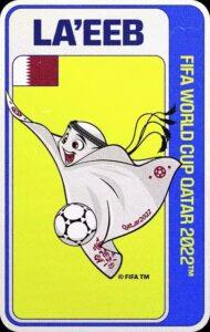 La'eeb, mascota oficial del Mundial Catar 2022, que representa una kufiyah blanca con detalles florales y futbolísticos decorativos, semiantropomórfica, por la presencia de una cara sonriente, cuyo cuerpo textil ondea mientras parece jugar al fútbol con el balón junto al cual aparece.