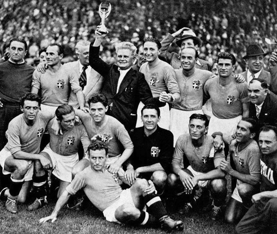 El entrenador, Vitorio Pozzo, levanta la copa Jules Rimet en el Estadio Olímpico de Colombes, tras ganar la Copa del Mundo de la FIFA en 1938; a su alrededor se encuentran los jugadores del equipo nacional de Italia y miembros técnicos de la Federación Italiana de Fútbol. De izquierda a derecha: en la fila superior, Burlando, Biavati, Vaccaro, Pozzo, Piola, Ferrari y Colaussi. En la fila inferior, LocatellI, Meazza, Foni, Serantoni (en el suelo), Olivieri, Rava y Andreolo.