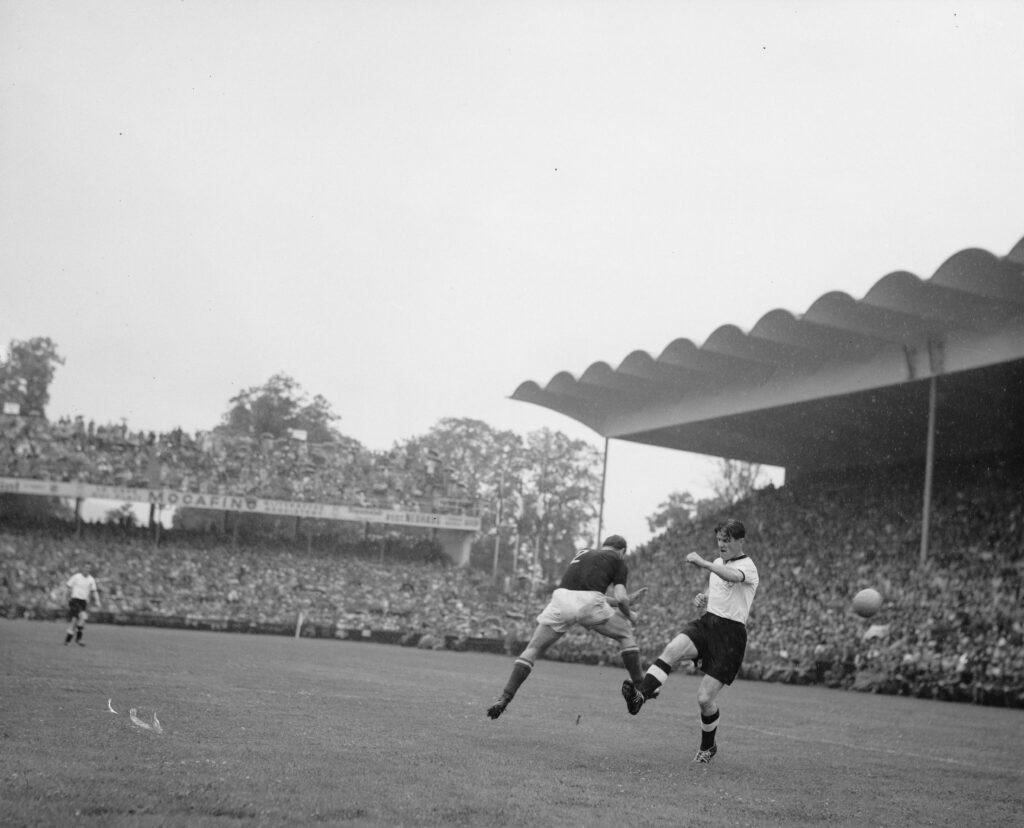 Fotografía de un momento del minuto 2 de la final de la Copa del Mundo Suiza 1954, en la que se encontraron los equipos de Alemania Federal y Hungría, celebrada en el Wankdorfstadion de Berna. En imagen, Al fondo, Fritz Walter (Alemania), y en primer plano, Buzansky (Hungría) y Ottmar Walter (Alemania), ambos con la pierna derecha levantada tras haberse disputado la posesión de un balón, que se encuentra en el aire a la derecha y detrás del jugador alemán, al haberse impuesto el húngaro.